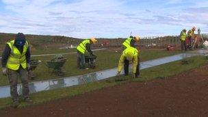 Workmen laying grass on Giant's Causeway centre roof