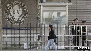 A woman walks past police officers standing guard outside the US embassy in Beijing on Saturday