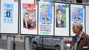 A man walks past candidates' election posters in Algiers