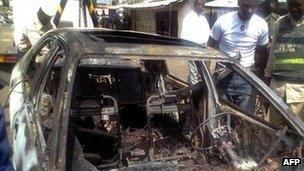 People gather around the car used to bomb This Day's office in Kaduna