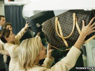 Women putting bags in overhead lockers