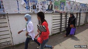 Women walk past electoral posters in Algiers May 9, 2012.