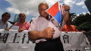 Protester Tsang Kin-shing, who supports Chinese sovereignty over the Scarborough Shoal, prepares to burn a paper Philippine and a US flag during a protest at the Philippine consulate