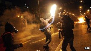 A protestor throws a molotov cocktail at riot police outside the parliament in Athens