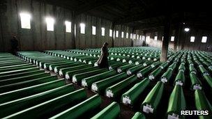 Woman walks past coffins containing the remains of war crimes victims in Potocari, near Srebrenica, on 9 July 2011