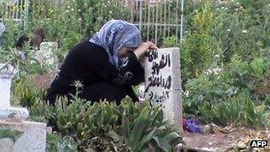 A Syrian woman mourns the death of a relative at a grave in the city of Rastan