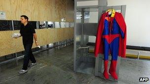 An employee walks past a Superman costume hanging on a phone booth door at the Facebook main campus in Menlo Park