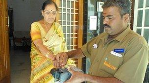 Woman in Mysore having fingerprint checked by gas man for ID number in pilot project