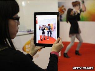 Woman uses Aurasma app on an iPad which displays a virtual 3D animation of a Thundercat character