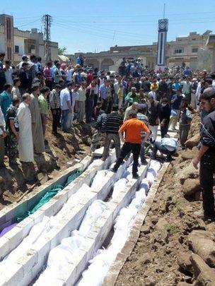 People gather at a mass burial for the victims purportedly killed by Syrian forces in Houla