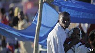 Haitian man holds a child in makeshift camp after the 2010 earthquake