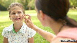 Girl having suncream applied