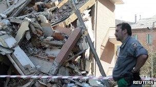 A rescue worker stands in front of a damaged building in Cavezzo