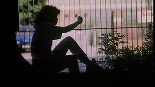 Silhouette of a girl looking through a park fence