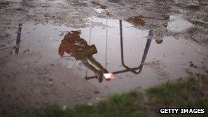 A child on a swing reflected in puddle