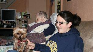 Girl with dog sits on couch while father with Alzheimer's sleeps