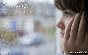 Child looking out at rain