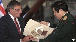 US Secretary of Defence Leon Panetta (L) hands his Vietnamese counterpart artefacts from the war