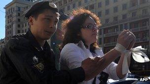 A police officer detains a protester wearing white ribbons, a symbol of the Russian opposition, outside the Duma June 5 2012