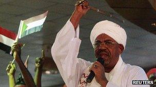 Supporters wave Sudanese flags as Sudan's President Omar al-Bashir addresses supporters during a rally at the ruling party headquarters in Khartoum, 18 April 2012