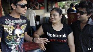 An Indian girl wears a t-shirt displaying a Facebook logo as she interacts with friends in Ahmadabad