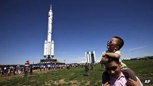 A Chinese father and son near the Long March-2F rocket carrying the Shenzhou-9 spacecraft