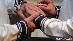 A man putting a wedding ring on another man's hand