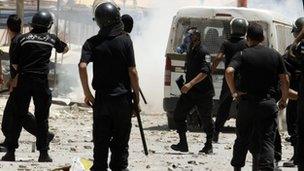 Riot police chase after protesters in the Ettadhamen district of the capital, Tunis