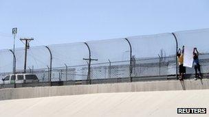 Two people hang up a banner at the US-Mexico border near Ciudad Juarez, Mexico 7 June 2012