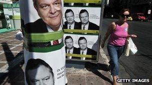 A woman walks by pre-election posters of Greek socialist party leader Evangelos Venizelos