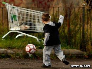 Child playing football near shopping trolley