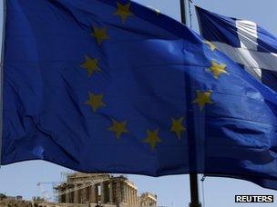 An EU and Greek flag flutter in front of the Parthenon, Athens