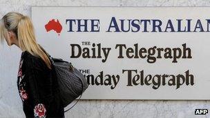 A woman walks past a sign outside the entrance to the News Limited building in Sydney on 20 June 2012