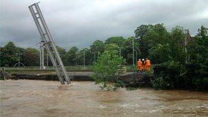 Overhead cable support for West Coast Mainline leans into the River Caldew