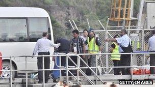 Rescued suspected asylum seekers arrive at Christmas Island after their boat capsized, on 22 June, 2012