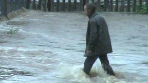 Man wading along flooded road