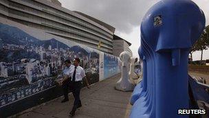 People walk past heavy fences outside the Hong Kong Convention and Exhibition centre where ceremonies marking the 15th anniversary of the handover of Hong Kong will be held, 28 June, 2012