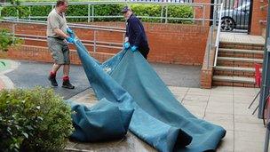 Staff clear up damaged carpets