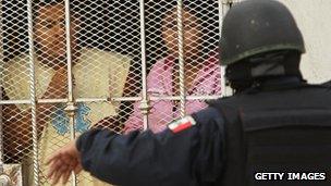 Residents speak with a police officer at the scene of a murder in 2010