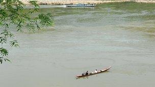 Laotian men fish from their boat in the Mekong river in Luang Prabang