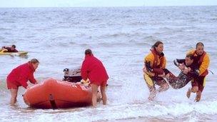 Two lifeguards carrying a 'casualty' from the water