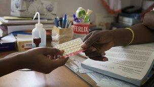 woman being handed contraceptive pills