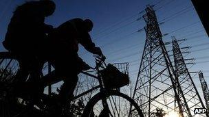 Chinese locals cycle past electricity cables