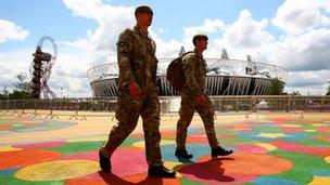 Two soldiers walk past the Olympic stadium in the Olympic Park