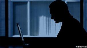 A man sits in the dark on a computer