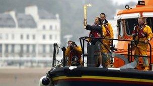 The torch is held aloft by security officer Suzia on board an RNLI lifeboat