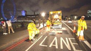 Workers painting and covering signs on Westminster Bridge in central London