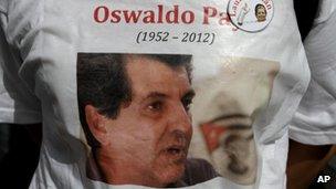 A dissident wears a T-shirt showing a photograph of Cuban activist Oswaldo Paya, centre, and of late dissident leader Laura Pollan, top right, during Paya's burial at a cemetery in Havana