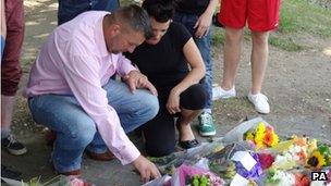 Jay Burgess, Carrie Valentine and teenagers look at floral tributes