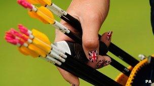 Woman with Union Jack nails selects arrow